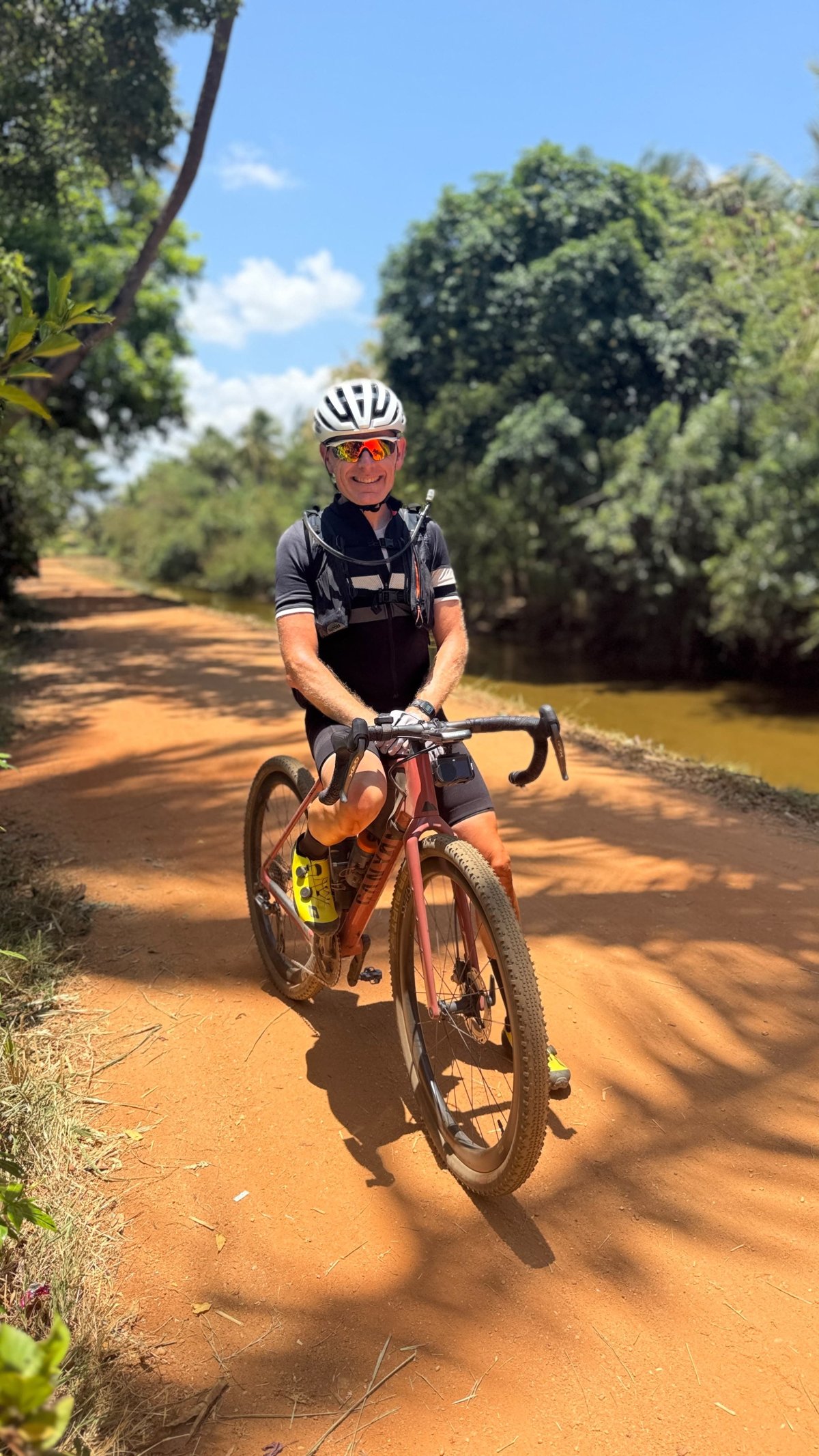Rider dressed and equipped for the heat on a shaded gravel road in Sri Lanka